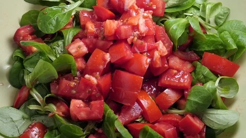 Salt spread on a mix salad of red organic juicy tomatoes and lamb lettuce salad Stock Footage 117137359