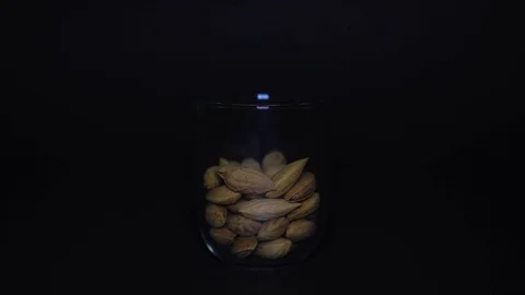 Salted almonds in shells in transparent glass on black background Stock Footage 75892056