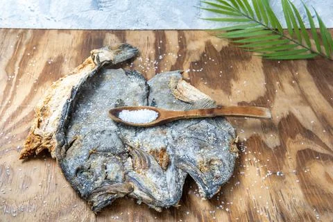 Salted cod with a spoon of sea salt and a palm leaf Stock Photos