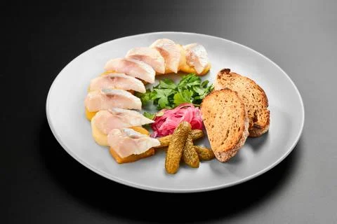 Salted mackerel with bread pickled vegetables grey plate black background menu Stock Photos