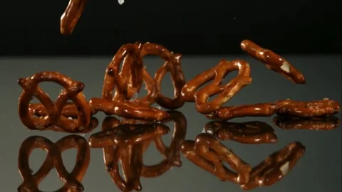 Salted mini pretzel snacks falling and bouncing on a surface Video stock 326750773