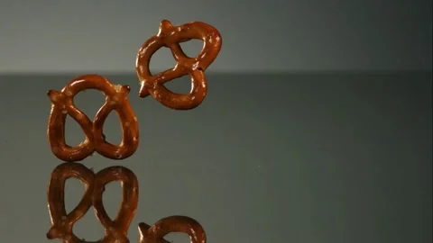 Salted mini pretzels bouncing on grey surface Stock Footage 327179802