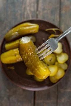 Salted pickled cucumbers on a fork in the foreground. in the background a pla Foto stock