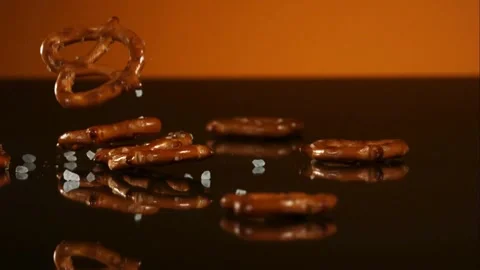 Salted pretzels bounce against solid orange background Video stock 326752450