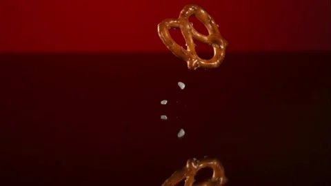 Salted pretzels falling and bouncing on a red surface Stock Footage 327631553