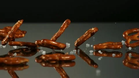 Salted pretzels falling on dark reflective surface Stock Footage 327050175