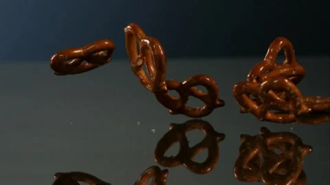 Salted pretzels falling on a reflective surface Stock Footage 327179691