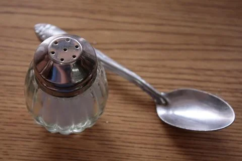 Saltshaker with a spoon on the table Stock Photos