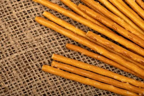 Salty bread strips scattered on a background of coarse homespun fabric. Stock Photos