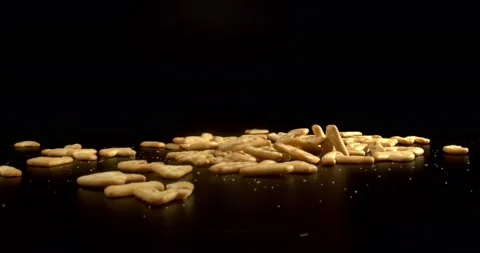 Salty Crackers falling on black surface, close up. Macro shot of tasty snack Stock Footage 148925655