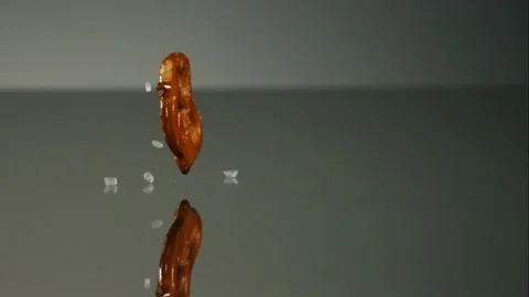 Salty pretzel snack falling on reflective surface Stock Footage 327180286