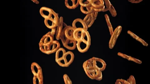 Salty pretzels fly and fall on a black background. Filmed on a high-speed camera Stock Footage 322797166