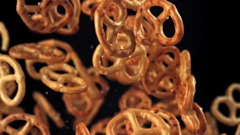 Salty pretzels fly and fall on a black background. Filmed on a high-speed camera Stock Footage 322797227