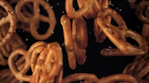 Salty pretzels fly and fall on a black background. Filmed on a high-speed camera Stock Footage 322807988
