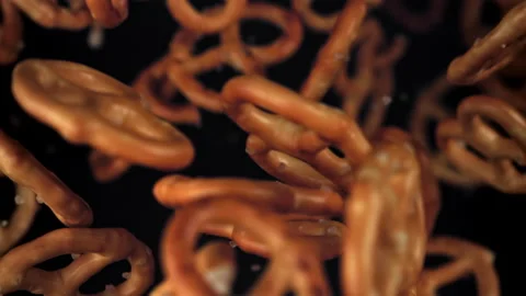 Salty pretzels fly and fall on a black background. Filmed on a high-speed camera Stock Footage 322822602