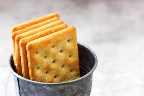 Salty rectangular crackers in a galvanized bucket on a gray background. Foto stock
