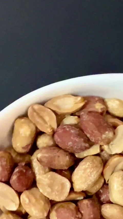 Salty roasted peanuts with skins in a white bowl Video stock 331983516