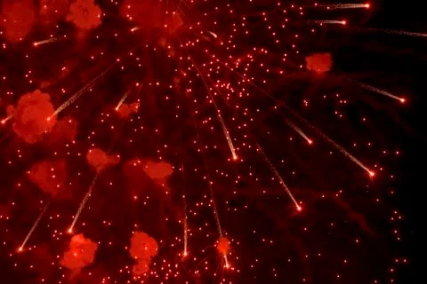 Salute. Bright, red splashes of fireworks in the dark sky. Stock Photos