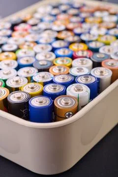 Samall AA batteries in a plastic box on a black table, ready to be recycled. Stock Photos