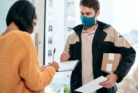 Same day delivery deserves a five star rating. a masked young woman signing for Stock Photos