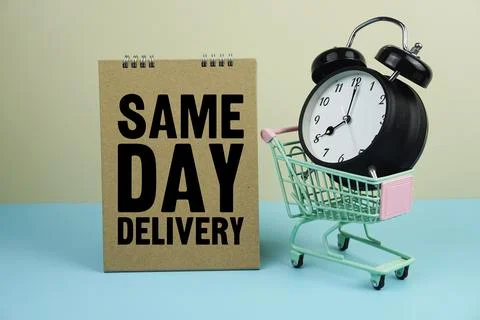 Same Day Delivery wiht mini trolley shopping cart and alarm clock on blue a.. Stock Photos