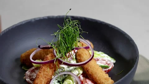 The same serving: breadcrumbs, red onion rings, tomatoes and greens on a salad  Stock Footage 313868813