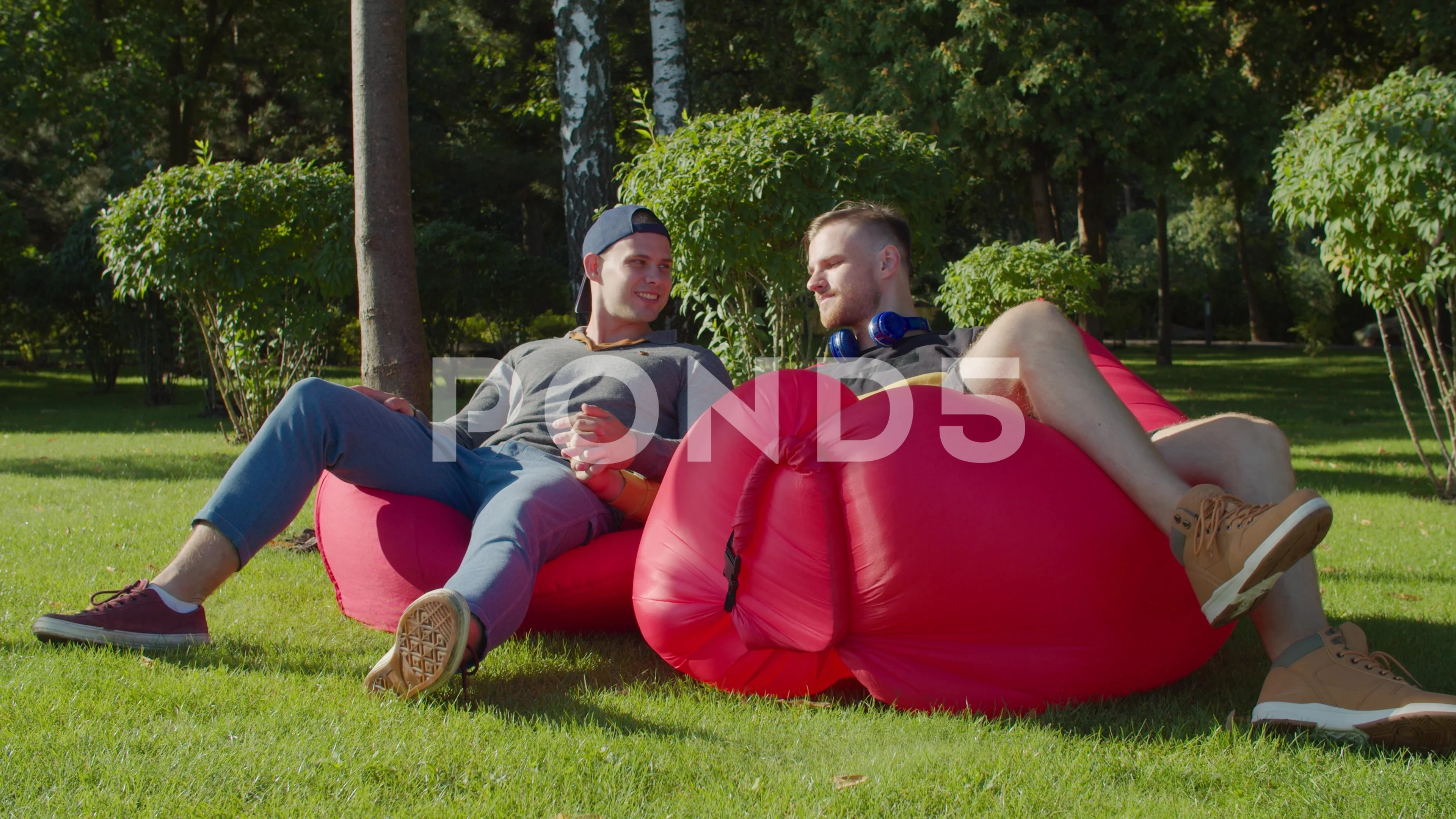 Same-sex couple relaxing on bean bags in nature