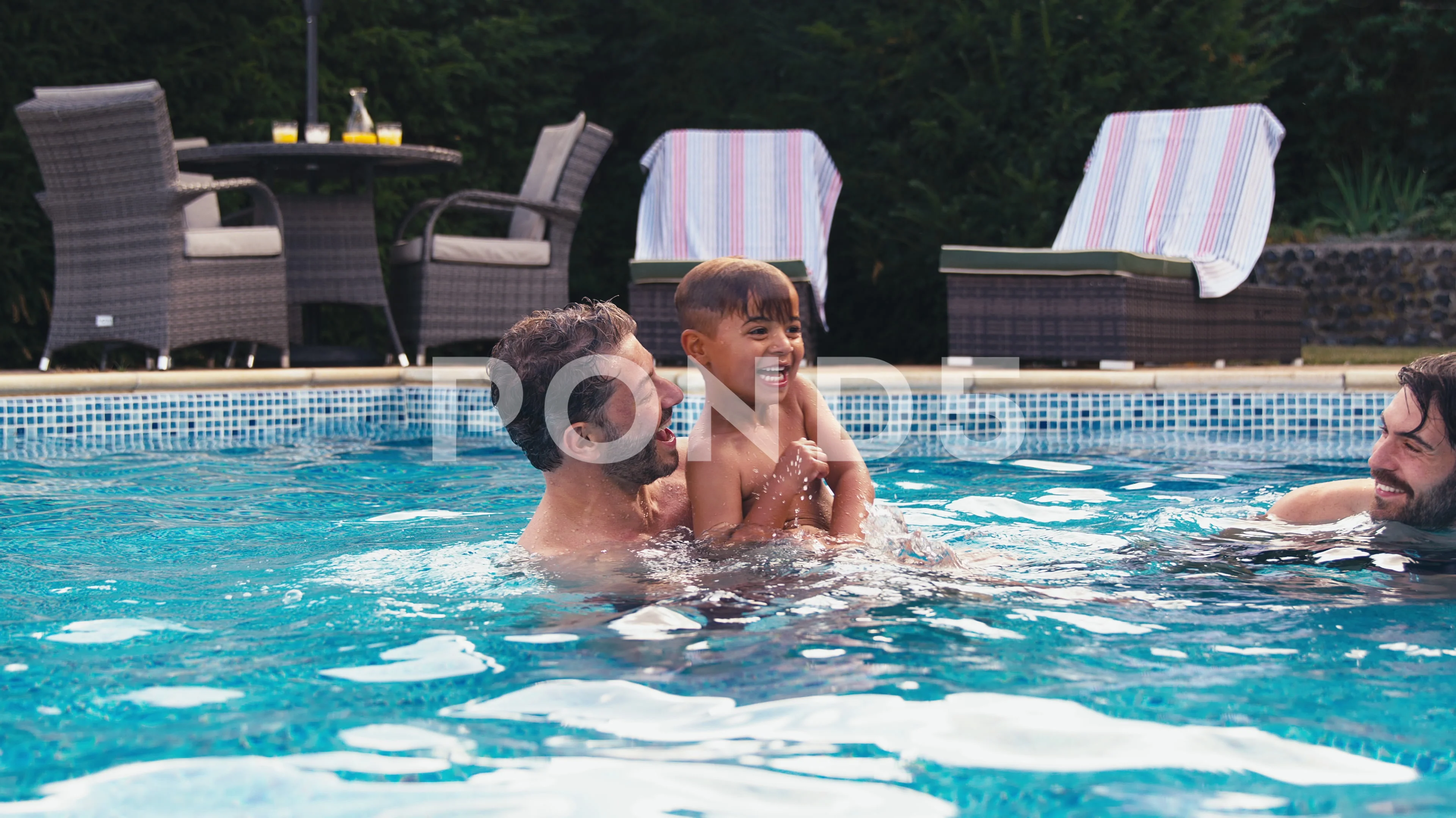 Same Sex Family With Two Dads And Son On Holiday In Swimming Pool Together