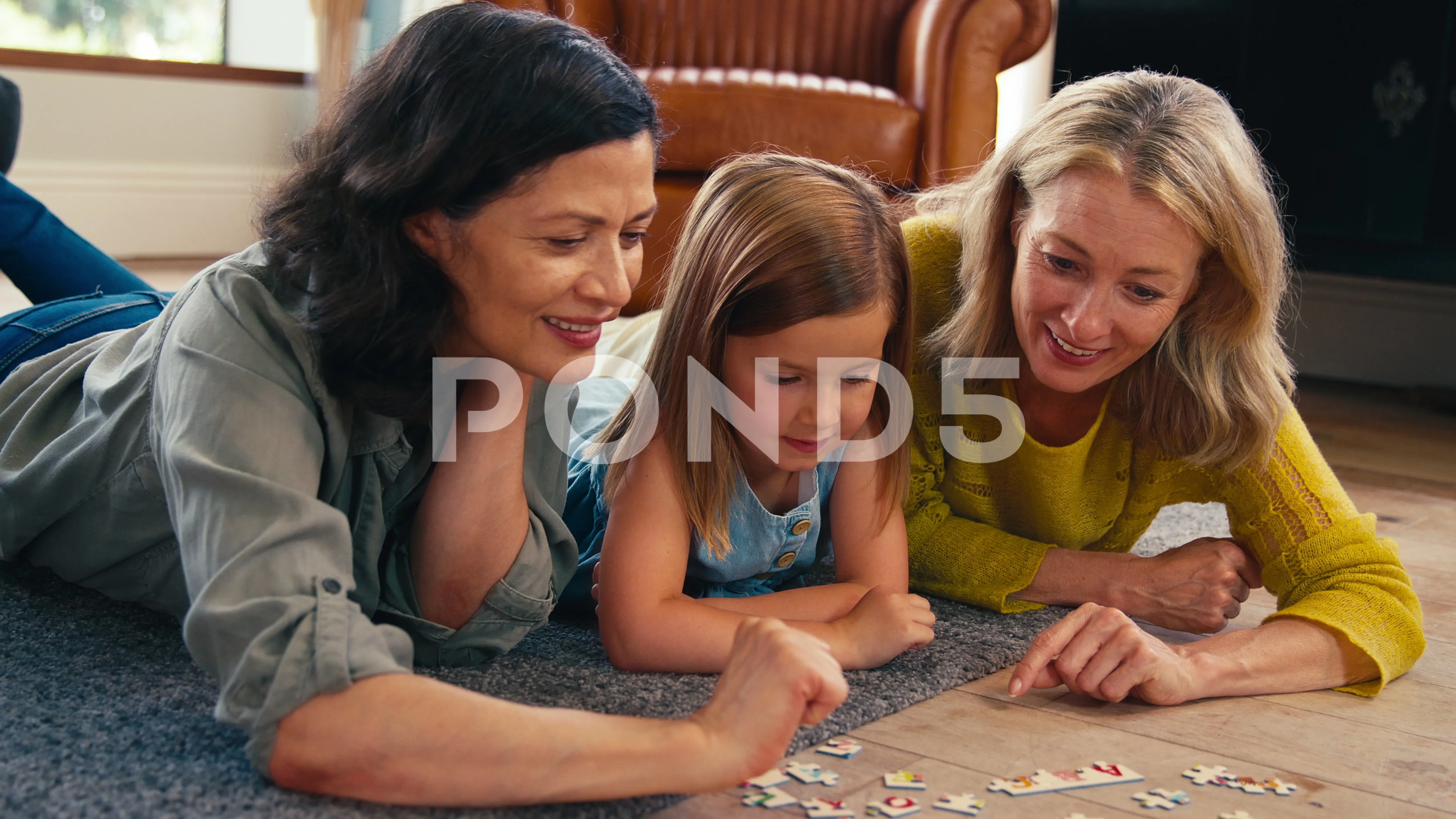 Same Sex Family With Two Mature Mums And Daughter Lying On Floor Doing  Jigsaw