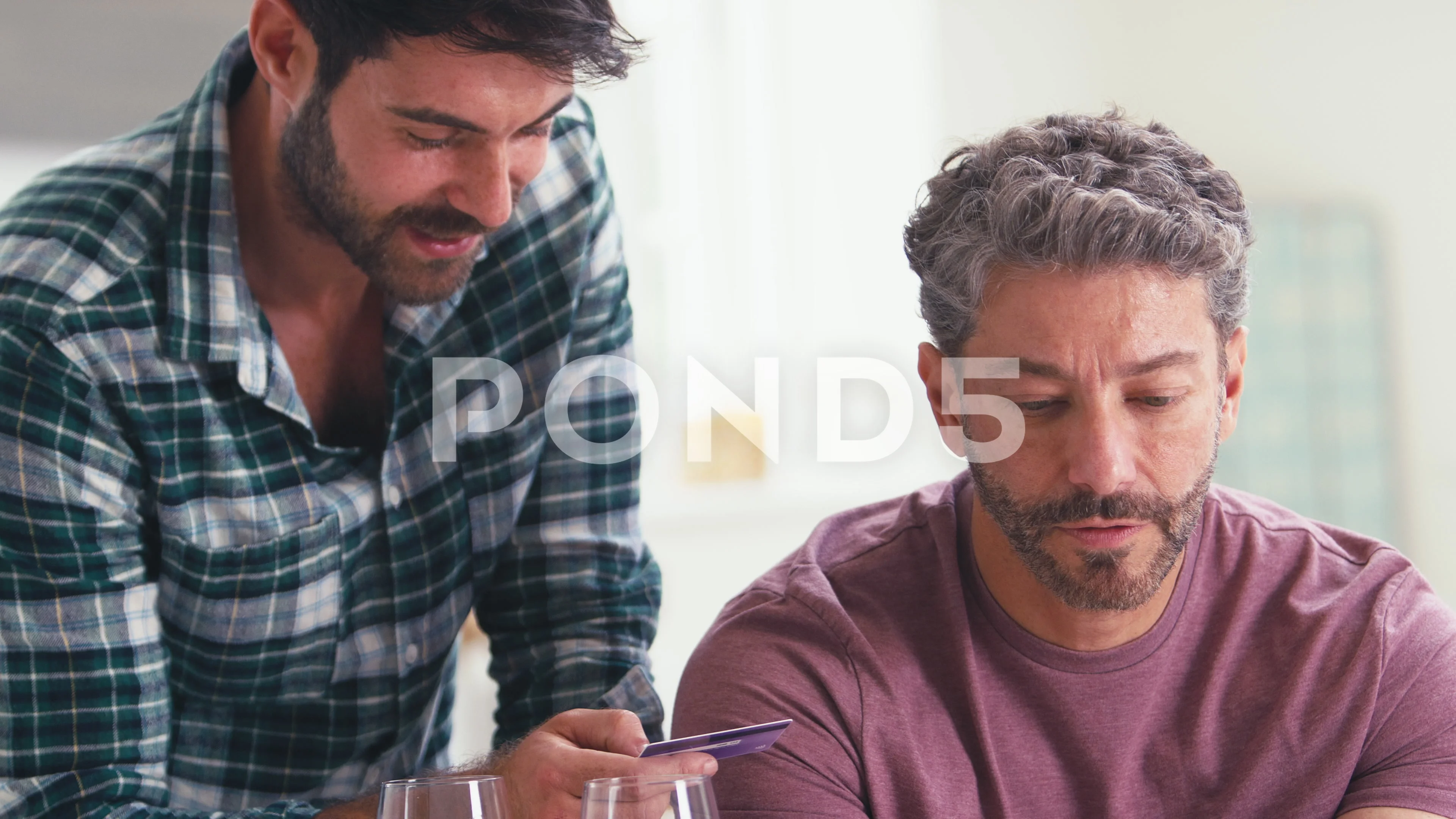 Same Sex Male Couple With Credit Card Using Laptop At Home To Book Holiday  Or