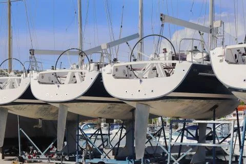 Same yachts stand in a row on the dry parking in the marina on a sunny summer Stock Photos