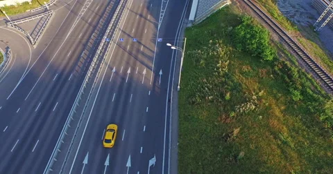 Сamera flies over the road, crossing overpass and follows the golden car. Stock Footage