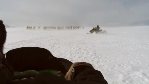 Sami sitting on a moving skidoo while herding the reindeer Video stock 107308313