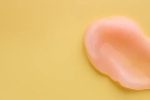 Sample of face cream on yellow background, top view. Space for text Stock Photos