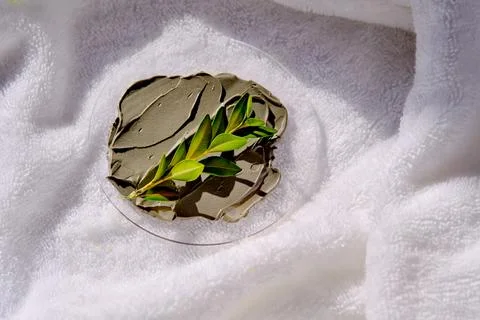 A sample of a mud mask on a terry bath towel with a green sprig. Foto stock