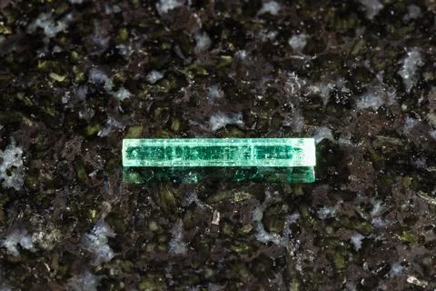 Sample of raw emerald crystal on black granite Stock Photos