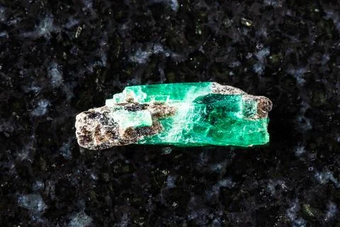 Sample of raw emerald crystal on black granite Stock Photos
