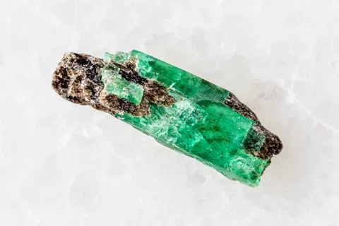 Sample of raw emerald crystal on white marble Stock Photos