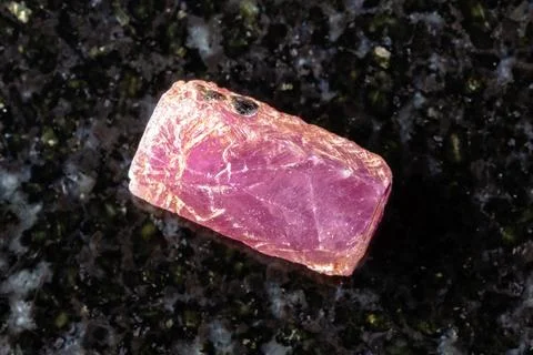Sample of raw pink ruby crystal on black granite Stock Photos