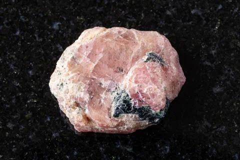 Sample of raw pink ruby mineral on black granite Stock Photos