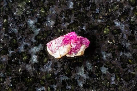 Sample of raw pink ruby mineral on black granite Stock Photos