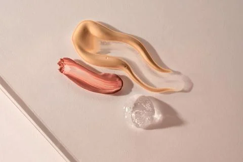 A sample of red lip gloss, foundation, powder and gel makeup base. Stock Photos