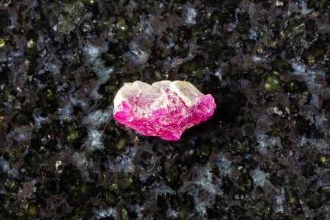 Sample of rough pink ruby mineral on black granite Stock Photos