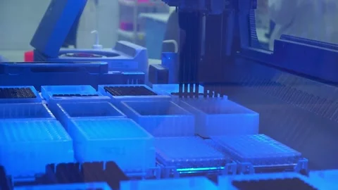 Sample trays and racks under blue light inside a DNA sequencing machine at a Stock Footage 345299419