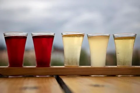 Sampler Flight Tray of Apple Cider Alcohol Drinks on a Wood Table Outdoors Stock Photos