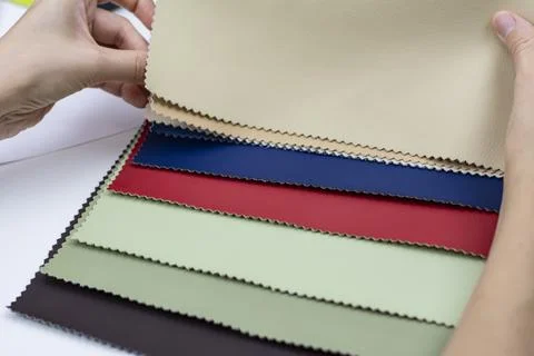 Samples of artificial leather. Female hands on sheets of leather close-up. Stock Photos