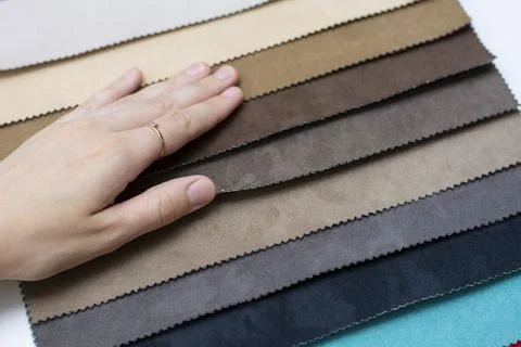 Samples of artificial suede. Women's hands on sheets of suede fabric close-up. Stock Photos