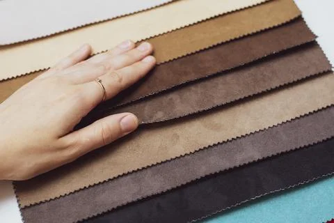 Samples of artificial suede. Women's hands on sheets of suede fabric close-up. Stock Photos