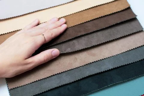 Samples of artificial suede. Women's hands on sheets of suede fabric close-up. Stock Photos