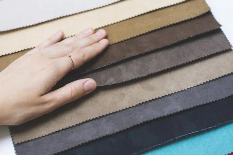 Samples of artificial suede. Women's hands on sheets of suede fabric close-up. Foto stock